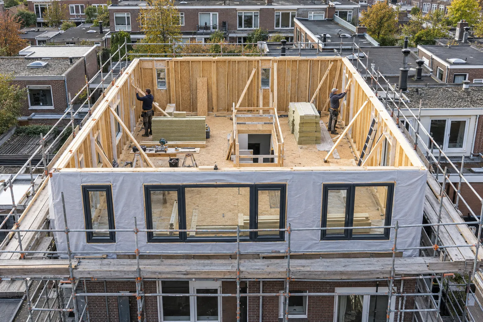 Houtskeletbouw van een dakopbouw op een plat dak, met steiger en zeil
