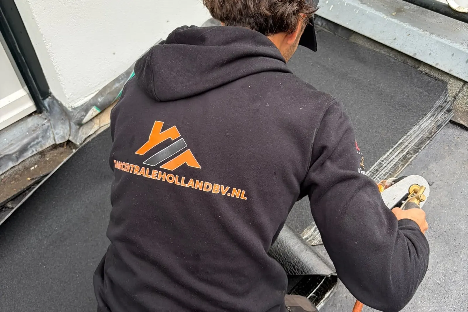 Dakdekker werkt loodwerk af bij de aansluiting van een plat dak