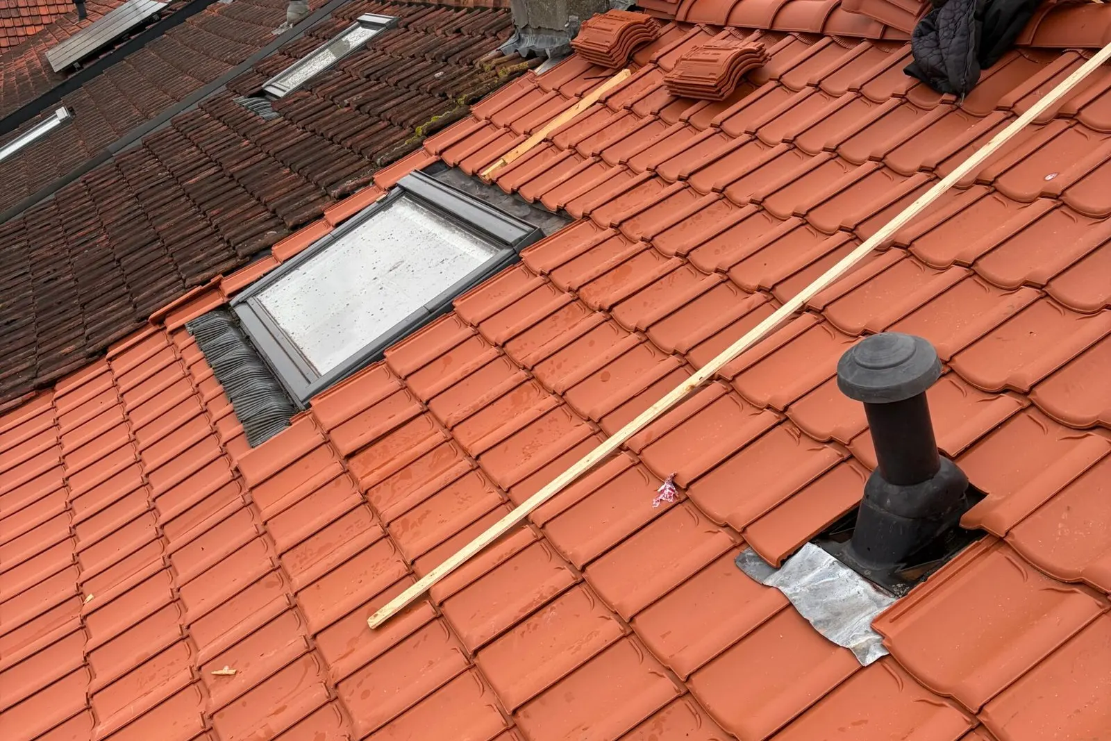 Oranje pannendak tijdens de renovatie met een nieuw dakraam en nieuwe panlatten