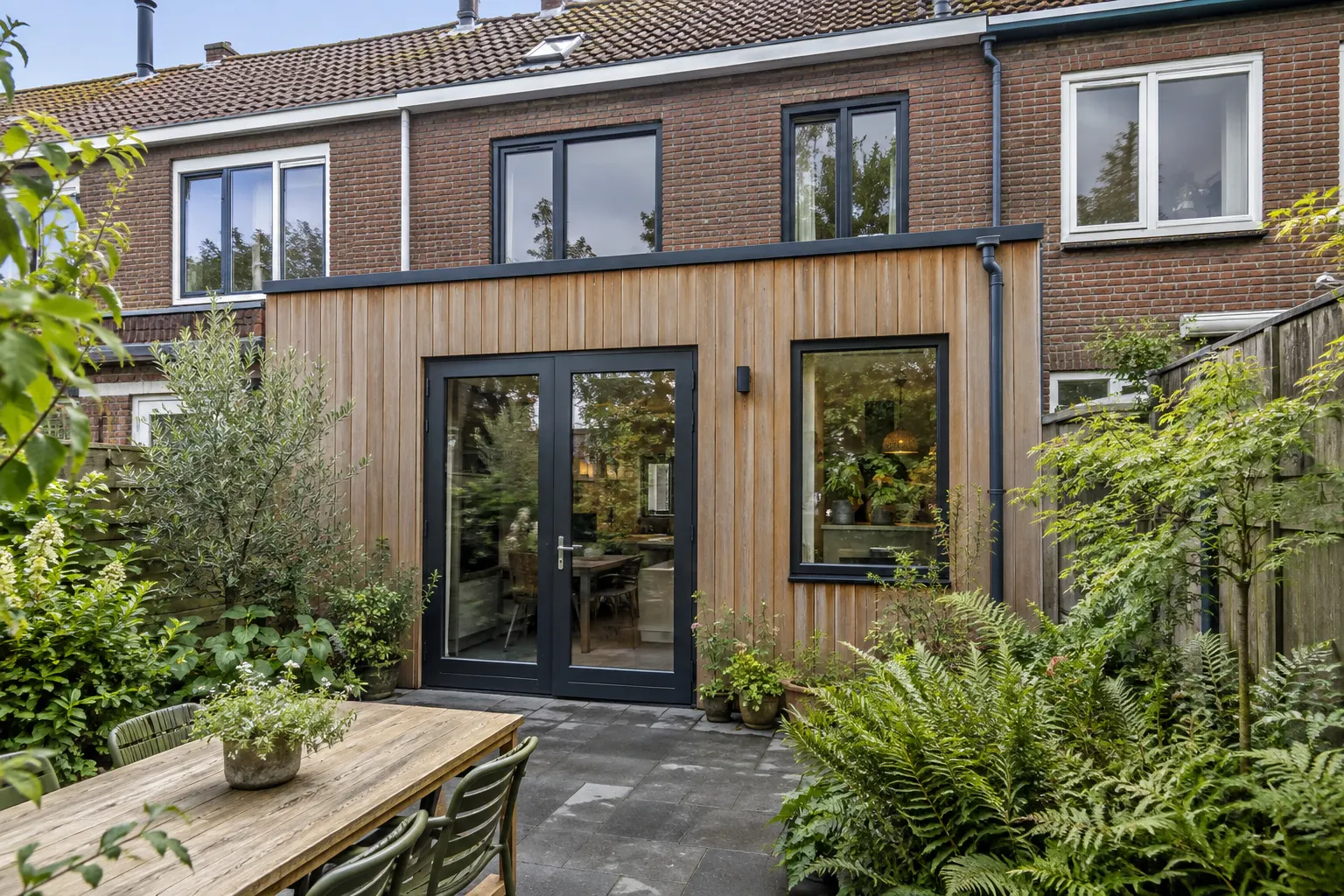 uitbouw met houten gevelbekleding en openslaande deuren