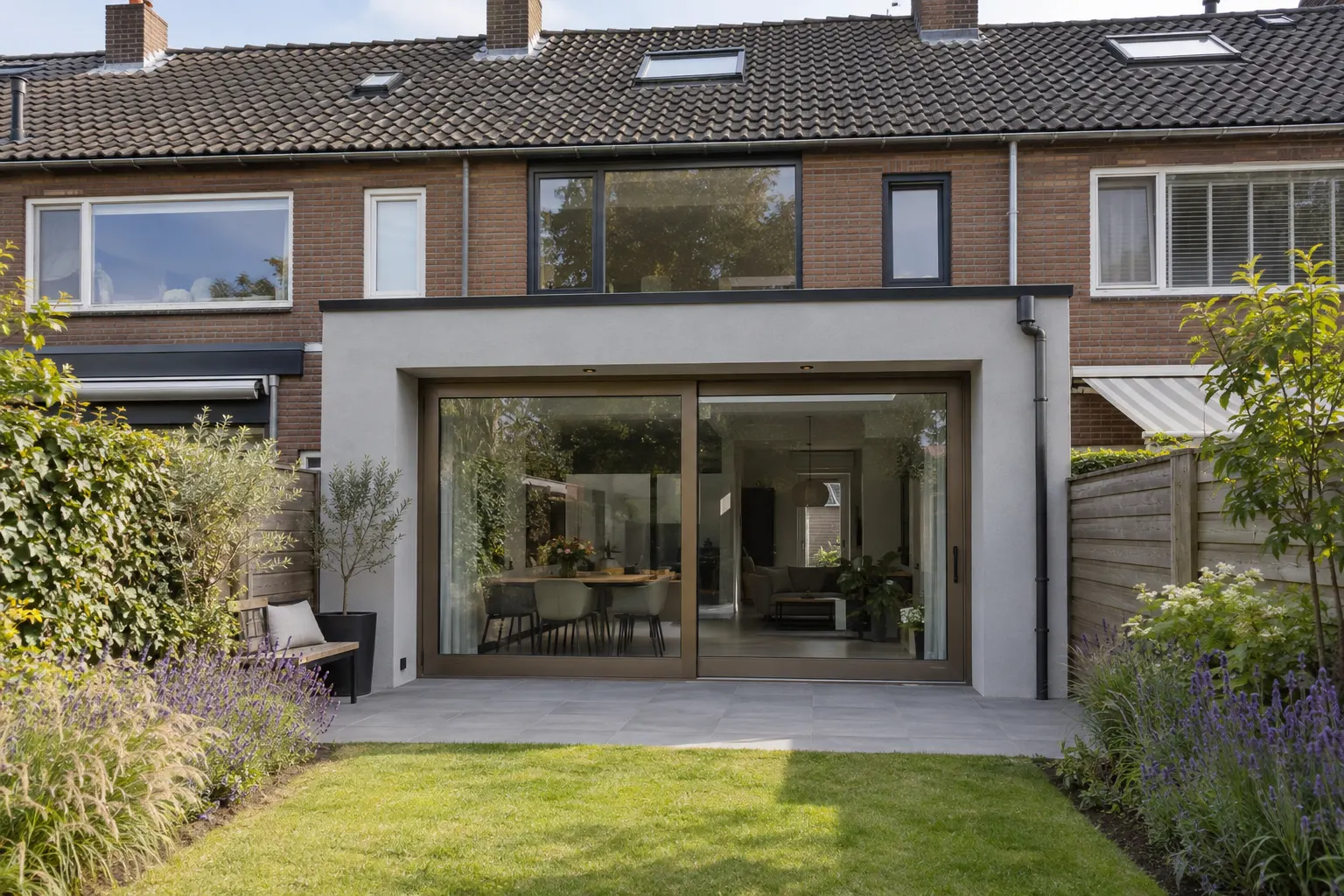 uitbouw in licht stucwerk met een schuifpui en een strak terras